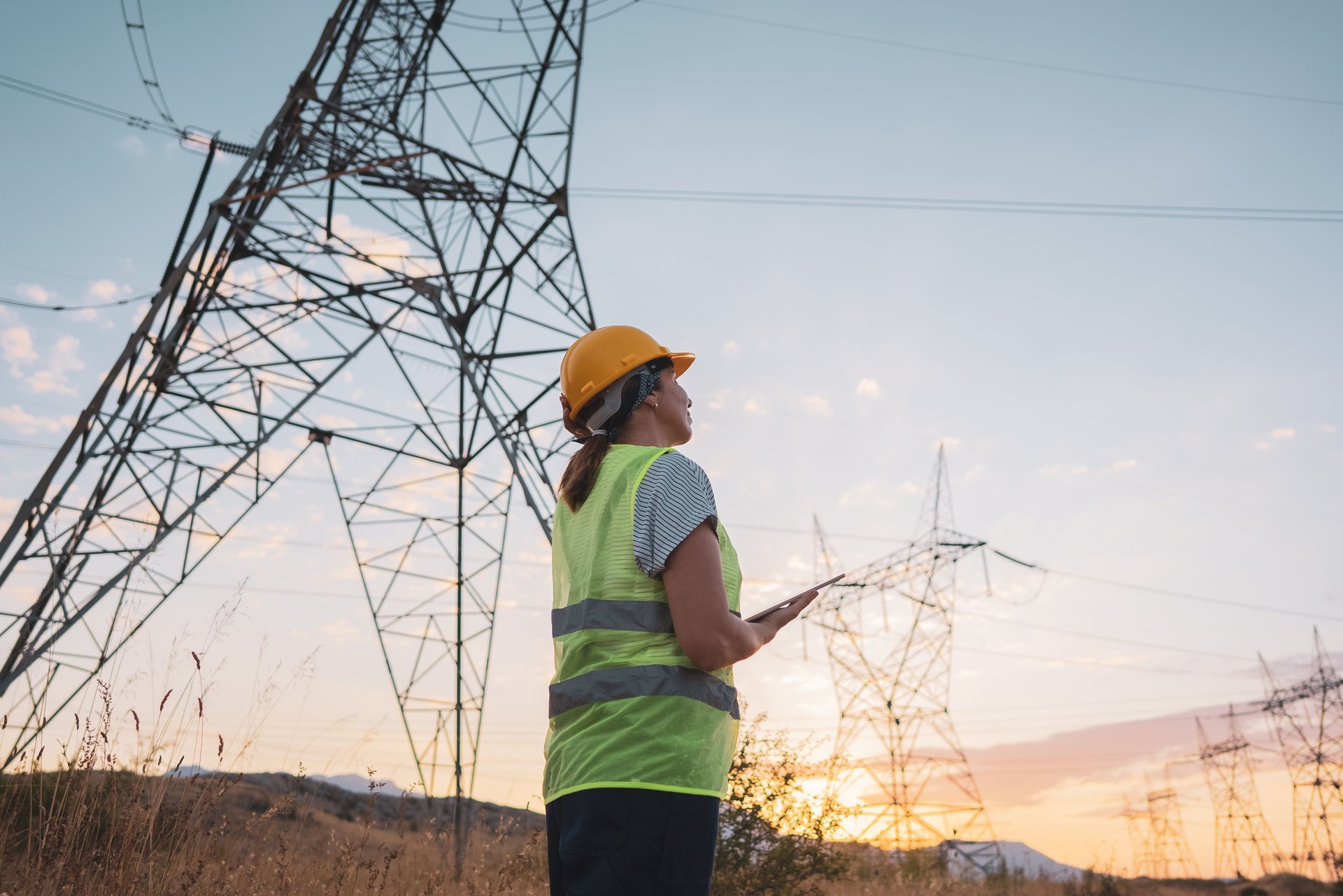 Female electrical engineer working near to High voltage tower.